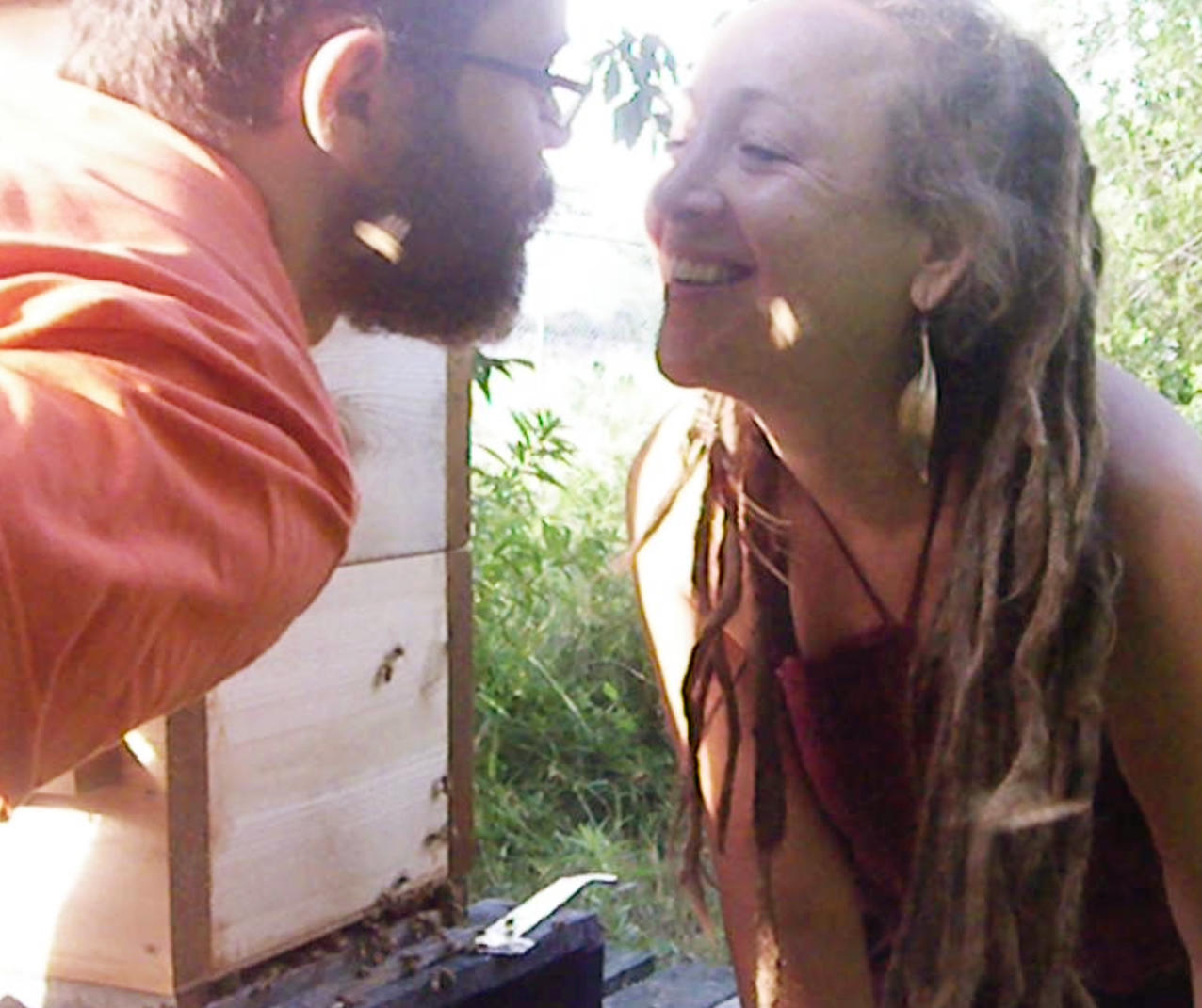 Couple gazing lovingly into each others eyes in front of hive